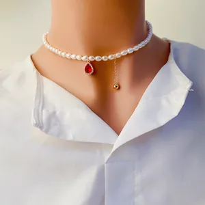 Gros plan d'un collier de perles d'eau douce avec pendentif en zircon rouge