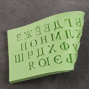 Gros plan d'un moule en silicone vert avec lettres cyrilliques pour décoration pâtissière