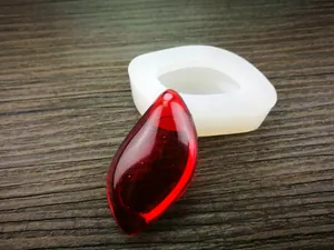 Détail du moule en silicone goutte d'eau et pendentif en résine rouge sur bois