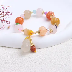 Nahaufnahme eines Armbands aus Naturjade mit Kürbisperlen und Flaschenkürbis-Anhänger.