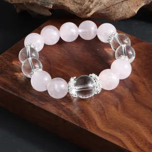 Vue détaillée d'un bracelet en perles de quartz rose et cristal sur support en bois