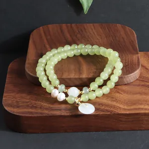 Detailaufnahme eines zweireihigen hellgrünen Edelstein-Armbands mit Perlen und Jade-Anhänger