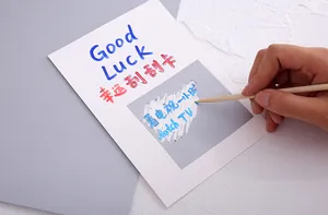 Close-up detail of a silver DIY scratch-off sticker being used with a wooden stick