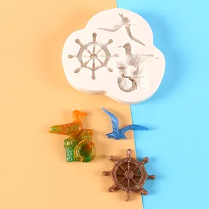Detail view of nautical silicone mold with finished resin seagull and ship wheel charms