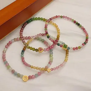 Dettaglio di braccialetti con perline di pietre naturali e ciondoli dorati.
