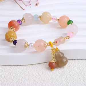 Detail eines ethnischen Perlenarmbands mit bunten Jade-Kürbisperlen und einem Anhänger.