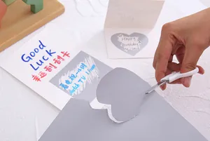 DIY heart-shaped silver scratch-off sticker being cut from a grey A4 sheet