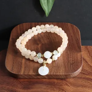 Detailaufnahme eines zweireihigen Sonnenstein-Perlenarmbands mit weißem Jadependant