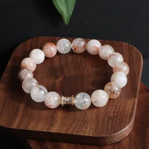 Detailansicht eines Super Seven Kristallarmbandes mit goldenem, kristallbesetztem Anhänger