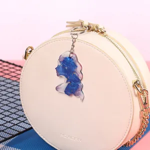 Blue and purple resin constellation pendant keychain on a cream round bag