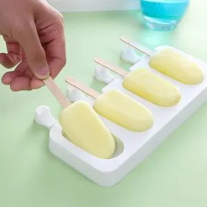Detailed view of pulling a fresh homemade yellow popsicle from a white silicone mold.