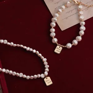 Detalle de collar y pulsera de perlas barrocas con colgante dorado Good Luck.