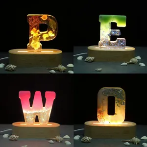 Detailed view of DIY resin alphabet lamps featuring dried flowers and glitter on LED bases
