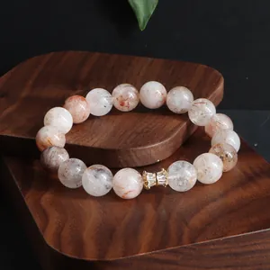 Nahaufnahme eines Super Seven Kristall-Armbands mit einem goldfarbenen Zirkonia-Element