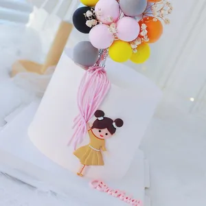 Primer plano de globos de colores y figura de niña para decoración de tartas de cumpleaños