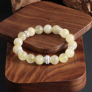 Detalle de pulsera de cuarzo rutilado dorado con espaciadores de flores plateadas grabadas