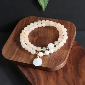 Detailansicht eines zweireihigen Sonnenstein-Perlenarmbands auf einem Holzständer.