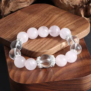 Gros plan des perles de quartz rose et de cristal sur un présentoir en bois texturé