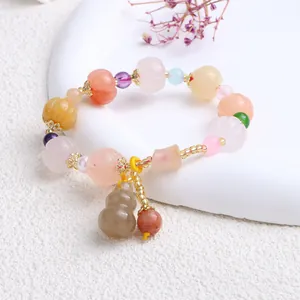 Nahaufnahme eines Armbands aus Goldseidenjade mit Kürbisperlen und Flaschenanhänger