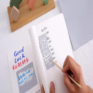 Close-up of hand using a tool to scratch off a DIY silver adhesive sticker on paper