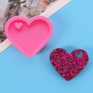 Close-up of heart-shaped silicone mold and a finished glittery resin heart pendant