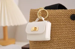 Detailansicht eines weißen Miniatur-Taschenanhängers an einer geflochtenen Tasche