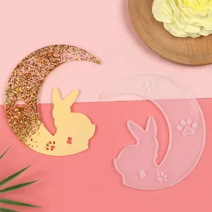 Detail shot of crescent moon and rabbit silicone mold alongside finished resin art