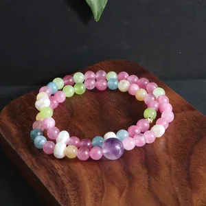 Detailopname van een dubbele armband met kleurrijke edelstenen en parels