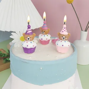 Close-up van drie schattige brandende cartoon beer partykaarsen op een blauwe taart