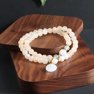 Nahaufnahme eines hochwertigen zweilagigen Sonnenstein-Armbands mit weißem Jade-Anhänger