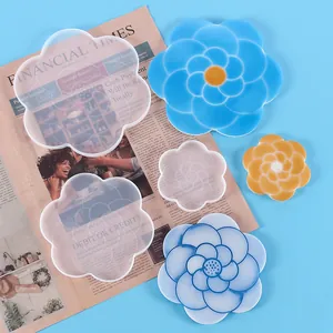 Detailed view of flower-shaped silicone molds and finished resin coasters on blue background.