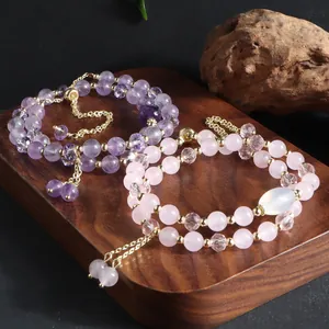 Close-up of natural amethyst and rose quartz double-layer bracelets with gold tassels.