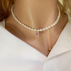 Détail d'un collier de perles d'eau douce avec pendentif en zircon rose et pompon doré