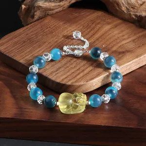 Detaillierte Makroansicht von blauen Achatperlen und Kristallarmband mit gelbem Pixiu-Anhänger