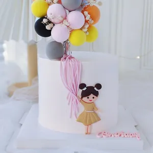 Vista detallada de una figurita de niña y globos de colores para decoración de pasteles