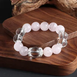 Vue détaillée du bracelet en perles de cristal rose et blanc sur plateau en bois naturel