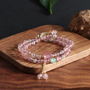 Detailed view of a natural strawberry quartz double-layer bracelet with gold accents