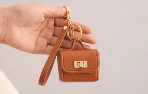 Detailansicht eines kleinen braunen PU-Leder-Münzbeutel-Schlüsselanhängers in der Hand.