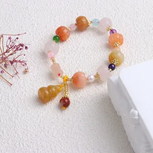 Detailaufnahme eines handgefertigten Jade-Perlenarmbands mit Kürbisperlen und Anhänger.