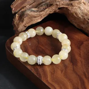Vista detallada de la pulsera de cuarzo rutilado dorado sobre un bloque de madera pulida