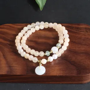 Detailansicht eines Armbands aus Sonnensteinperlen mit einem weißen Jade-Anhänger