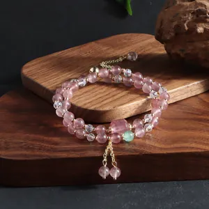 Macro detail of strawberry quartz double-strand bracelet with golden tassels