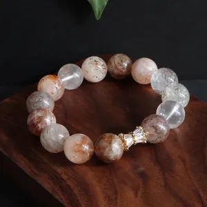 Nahaufnahme eines natürlichen Super Seven Kristall-Perlenarmbands mit Gold-Deko-Element.