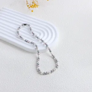 Collier de perles rétro colorées présenté sur un plateau blanc à texture ondulée