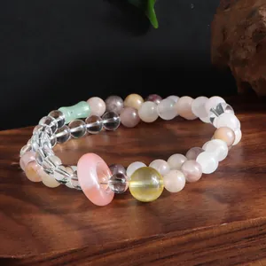 Close-up of double-strand crystal bracelet with rose quartz donut charm on wooden base