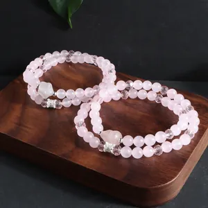 Gros plan de bracelets double couche en quartz rose avec pendentif coeur sur bois
