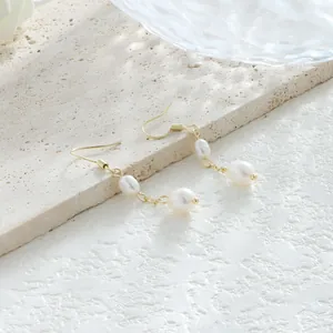 Detalle de pendientes de perlas barrocas con ganchos bañados en oro de 14K sobre piedra