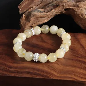 Pulsera de cuarzo rutilado dorado natural con cuentas de flores de plata sobre madera
