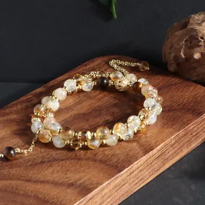 Exquisite close-up of natural citrine and tiger eye double-strand bracelet on wood.