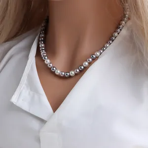 Gros plan d'un collier de perles de nacre colorées sur un mannequin avec chemise blanche